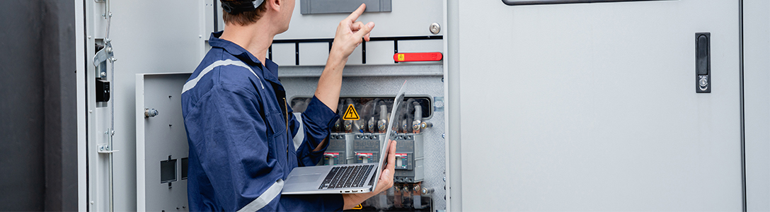 Engineer with laptop in front of SCADA system Engineer with laptop in front of SCADA system